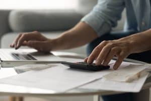 Close up of young male accountant hands make audit of expenses calculate charges based on paper documents.