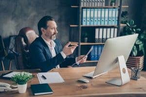 Happy businessman having a discussion online sitting at his desk