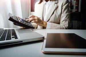 Young businesswomen use calculator at his desk with laptop and tablet placed on the table