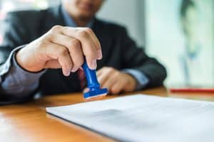 Businessman stamping with approved stamp on document at the meeting