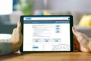 Closeup view of a human hand holding a tab that is displaying RMAi website